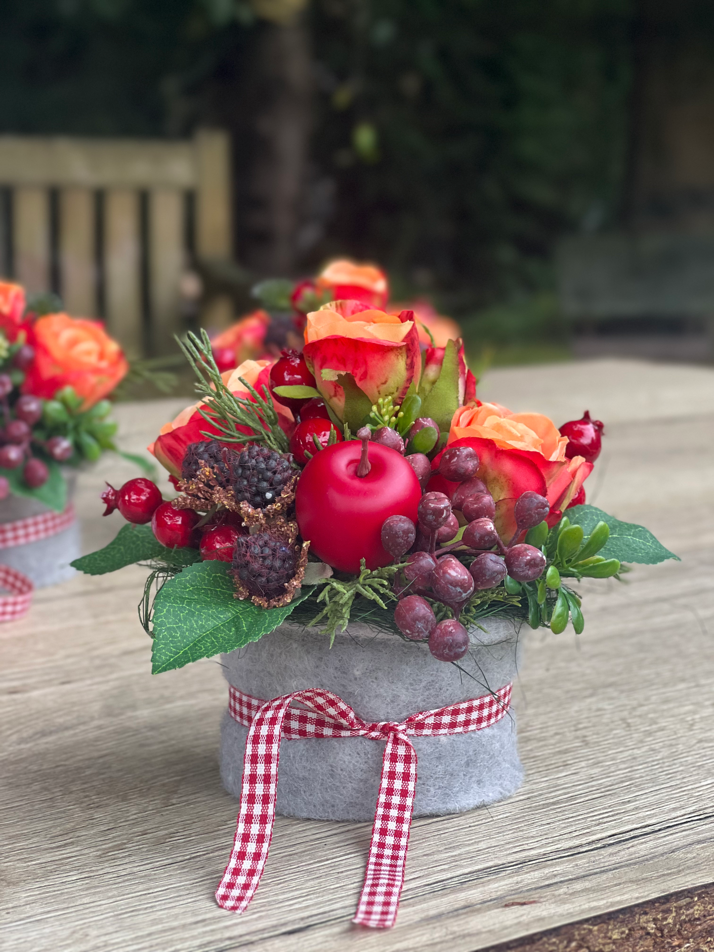 Herbstliches Blumengesteck mit orangen Rosen und Beeren