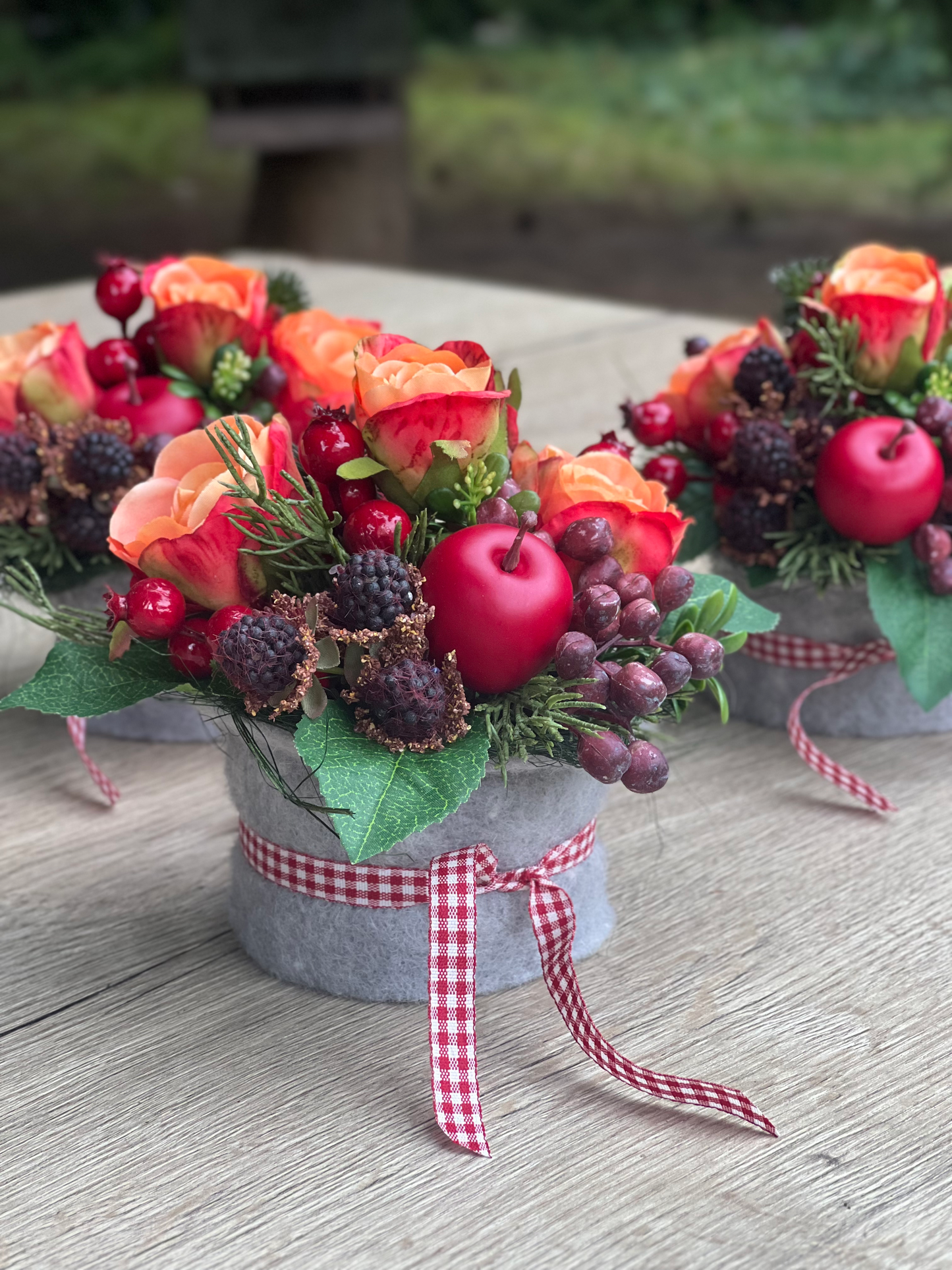 Herbstliches Blumengesteck mit orangen Rosen und Beeren