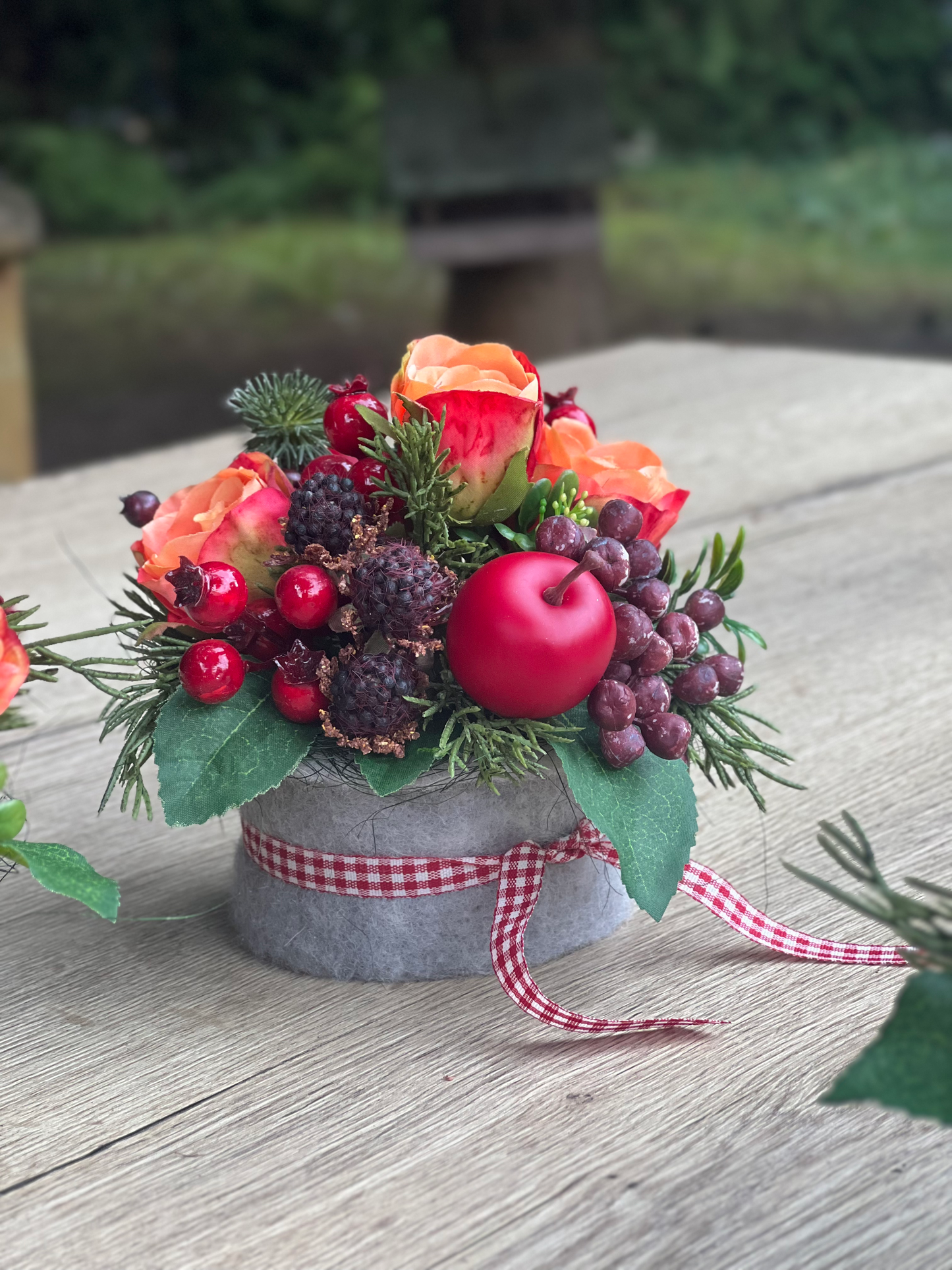 Herbstliches Blumengesteck mit orangen Rosen und Beeren