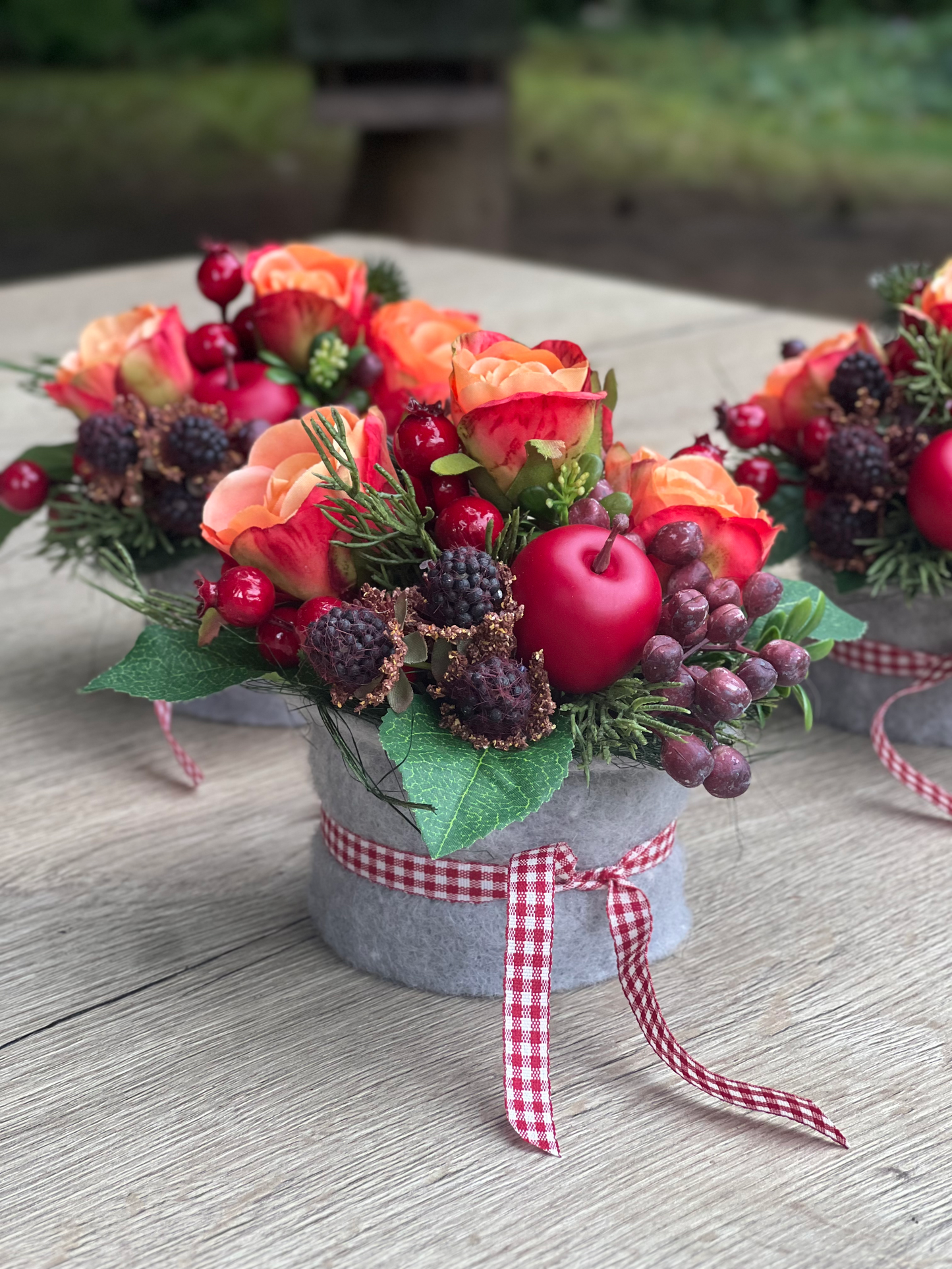 Herbstliches Blumengesteck mit orangen Rosen und Beeren
